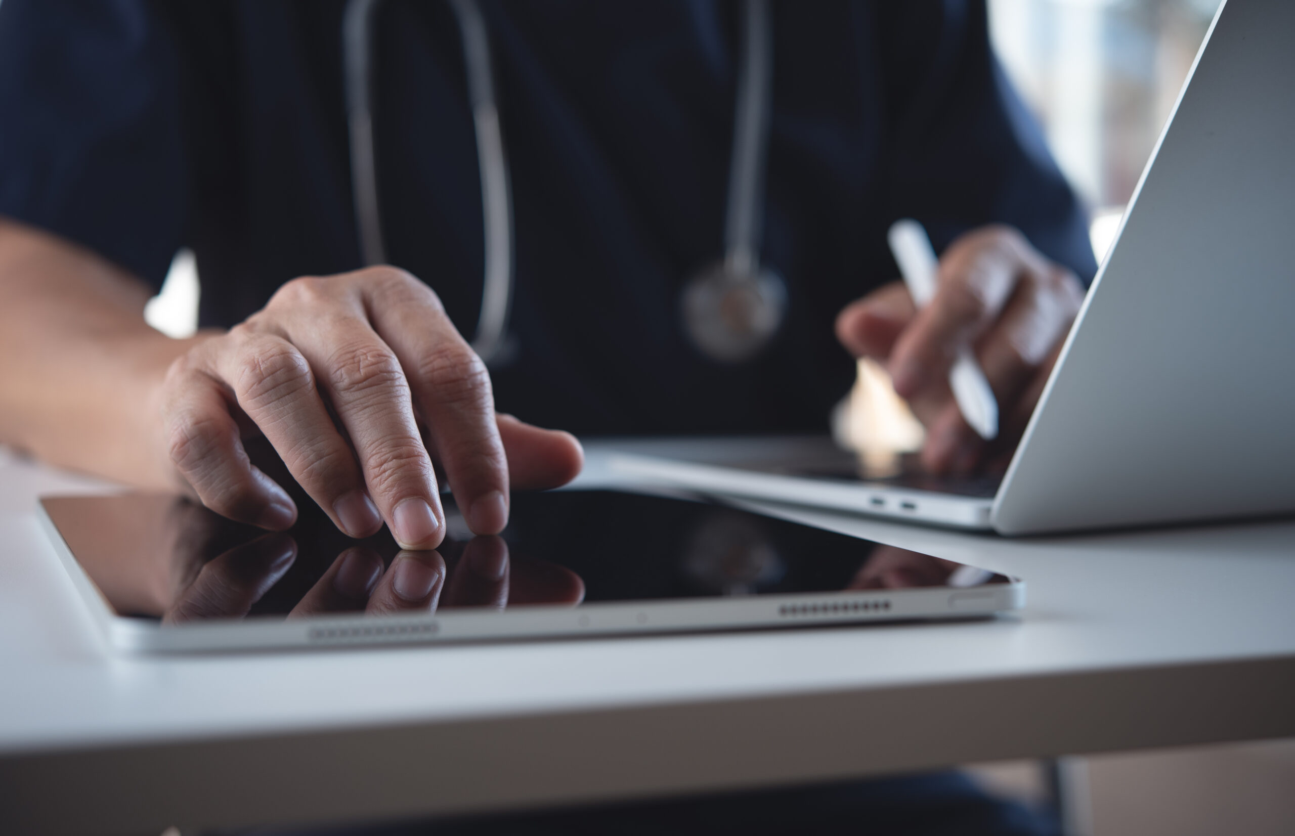 Close up of doctor, sugeon using digital tablet and laptop computer during working in doctor's office, healthcare and medicine, electronic health record system concept